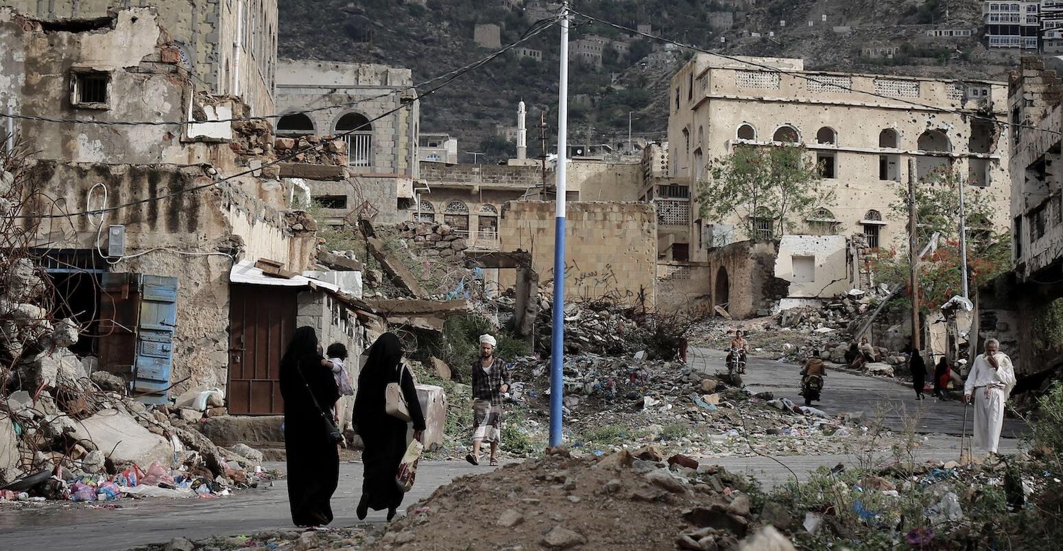 People walk on the rubble of houses destroyed by war in Taiz, Yemen.