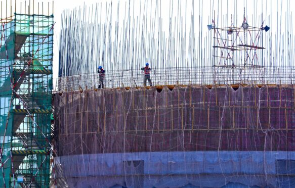 Builders bundle steel frames at a coal construction site in Gansu, China.