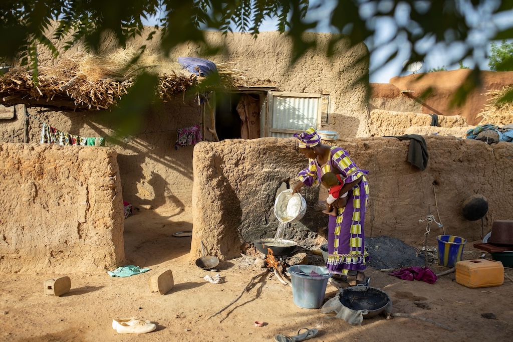 An African woman cooks over an open fire outside home in Mali, West Africa.
