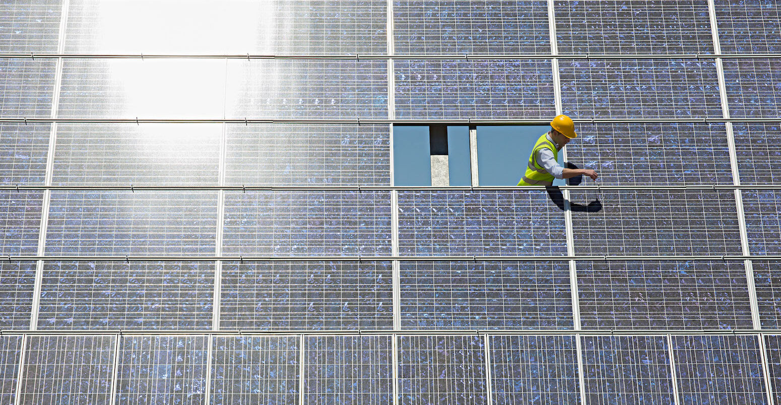 Worker examines solar panel.