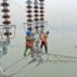 Construction workers inspect power transmission tower.