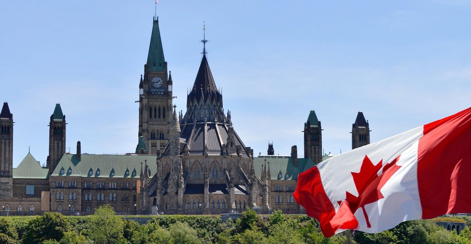 Canadian parliament buildings and Canada flag. Credit: Colin Clarke / Alamy Stock Photo. Image ID: WB161K.