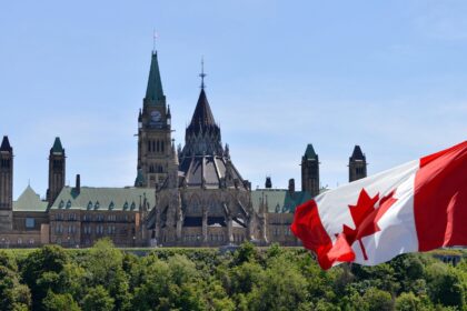 Canadian parliament buildings and Canada flag. Credit: Colin Clarke / Alamy Stock Photo. Image ID: WB161K.