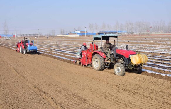 Farmers ploughs land with tractors in Hebei province, China.