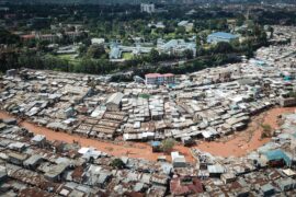An aerial photo of slums in Kenya with flooding travelling through the middle of the informal settlement.
