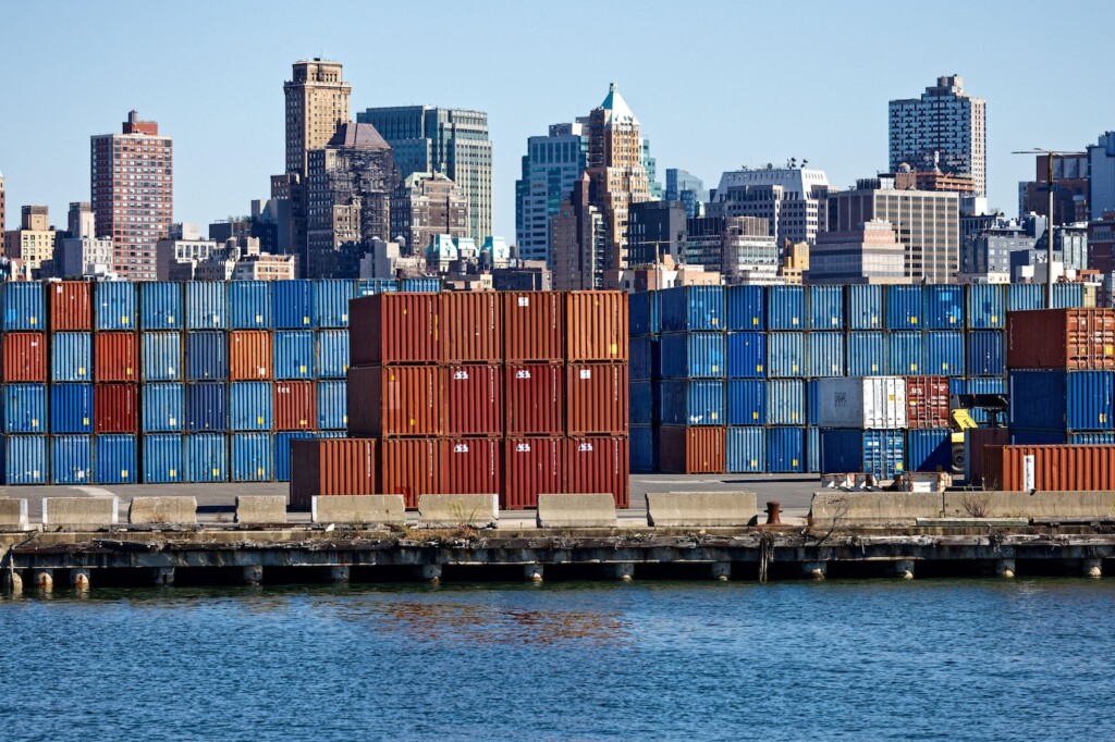 Stacks of shipping containers at Red Hook Container Terminal against Brooklyn skyline, US.