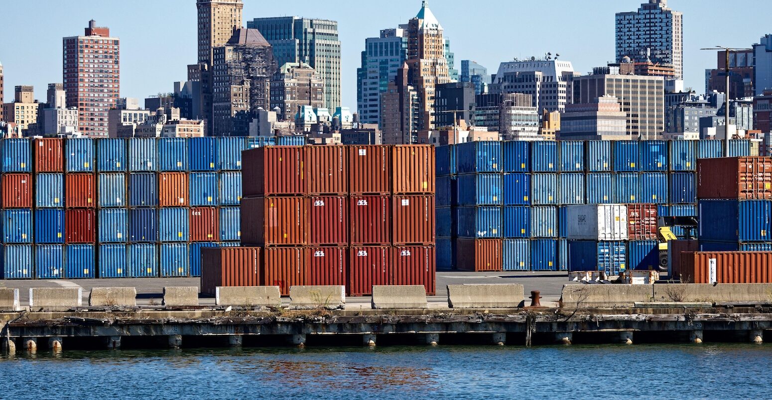 Stacks of shipping containers at Red Hook Container Terminal against Brooklyn skyline, US.