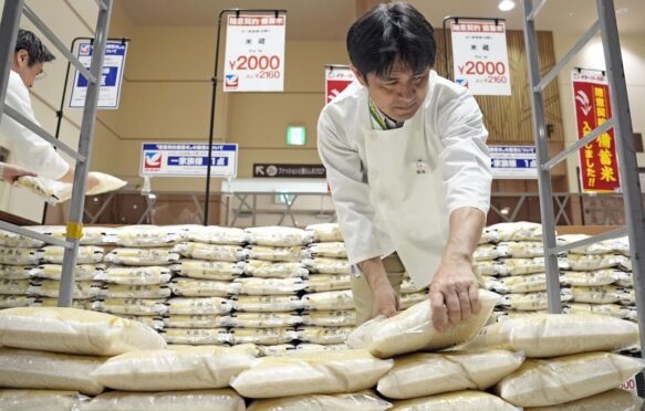 supermarket worker handles bags of reserve rice released from government stockpiles in Tokyo on 31 May 2025.