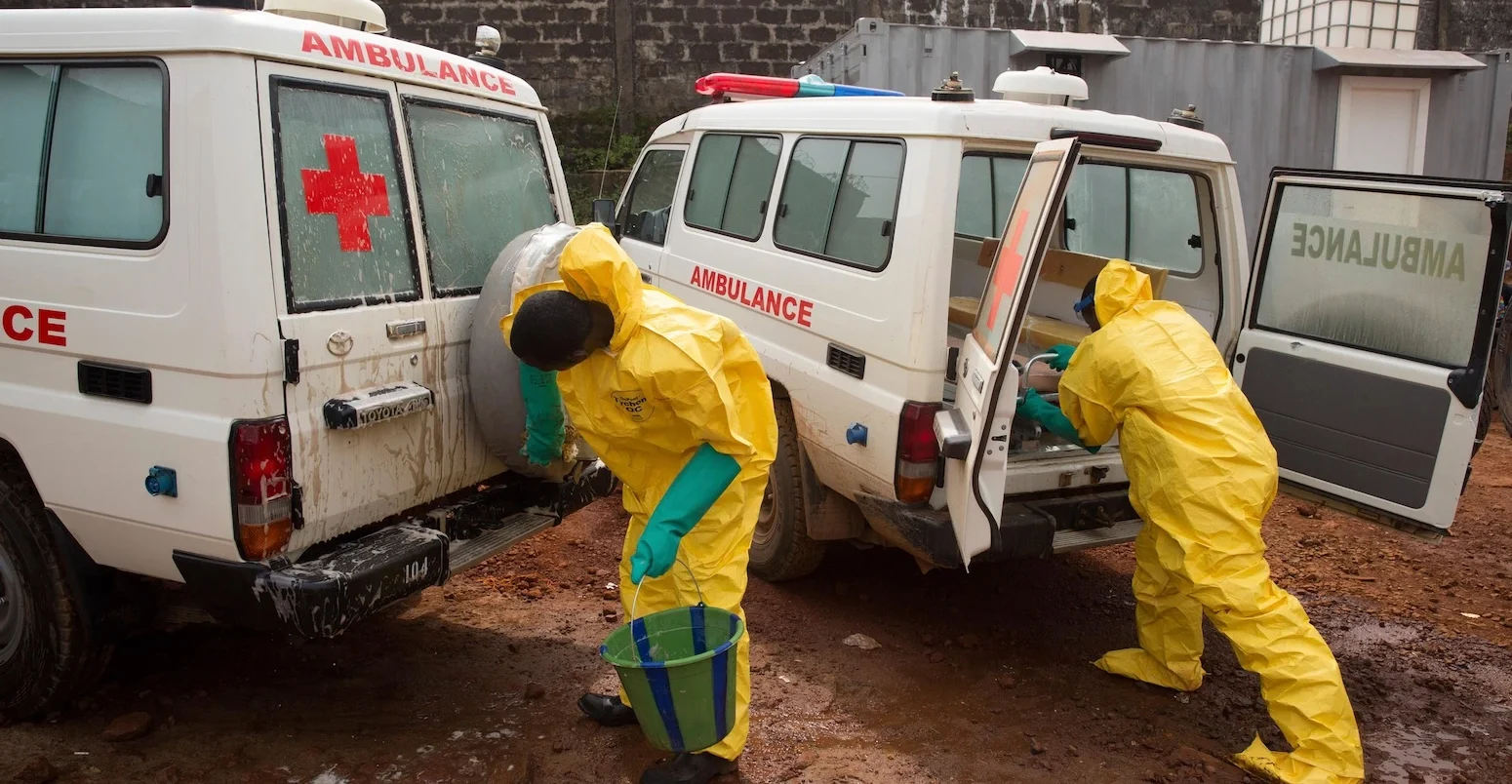 Ambulance drivers in protective clothing disinfect their ambulances, Sierra Leone. - Image.