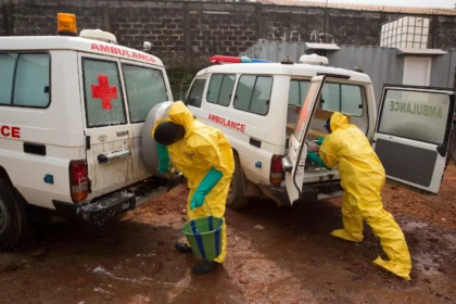 Ambulance drivers in protective clothing disinfect their ambulances, Sierra Leone. - Image.