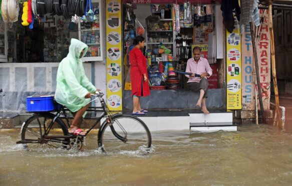 A cyclist goes through heavy rain and flooding in Mumbai, India.