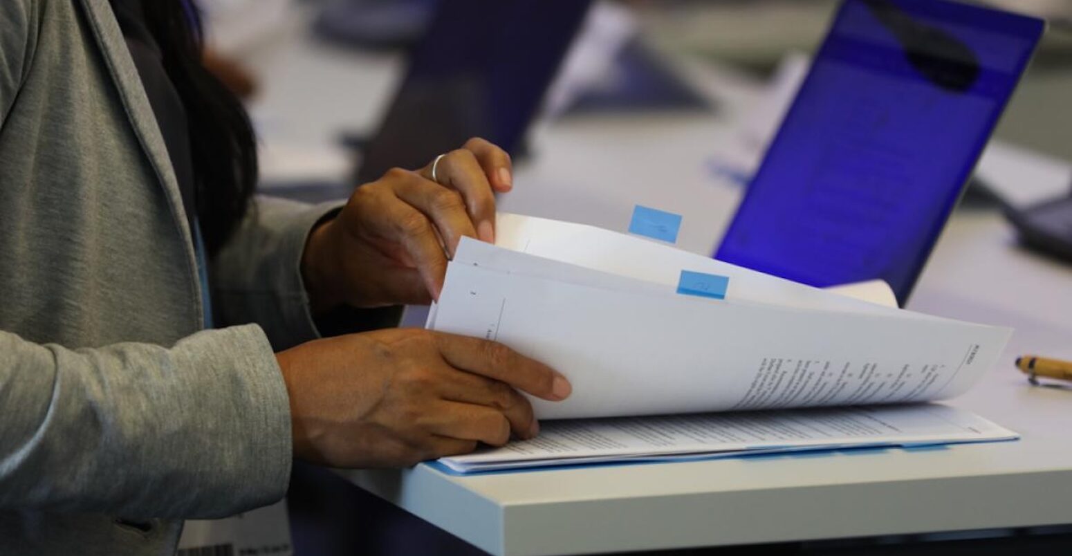 A delegate checks documents at a UNFCCC event. Credit: IISD/ENB - Kiara Worth.