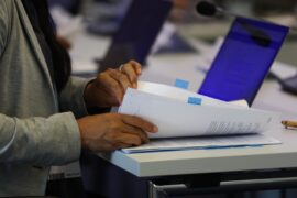 A delegate checks documents at a UNFCCC event. Credit: IISD/ENB - Kiara Worth.