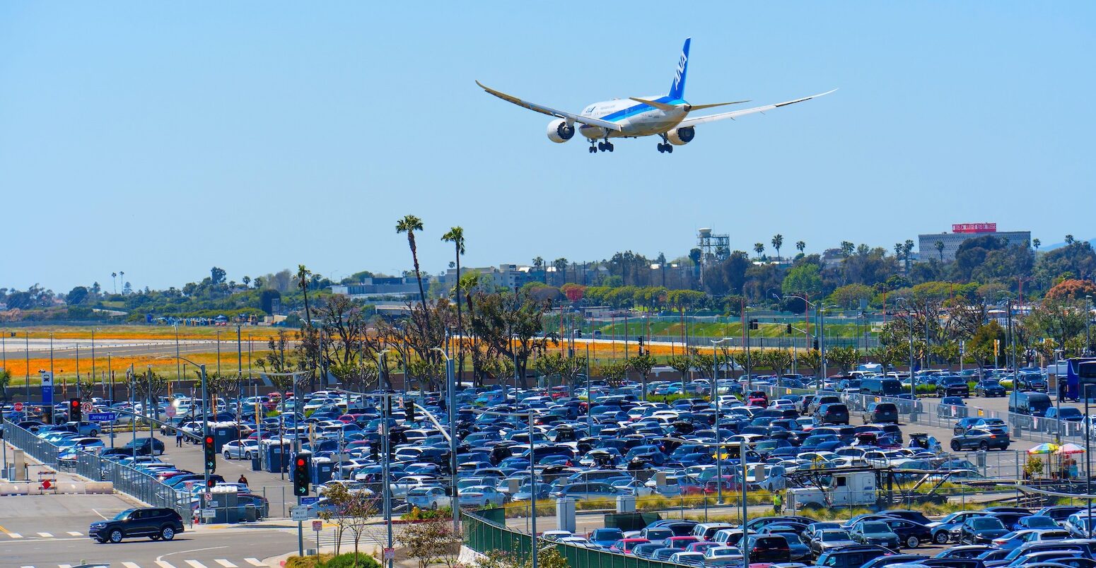 Close-up view of the tightly packed LAX Parking lots with an airplane flying above.