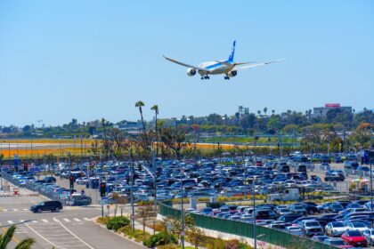 Close-up view of the tightly packed LAX Parking lots with an airplane flying above.