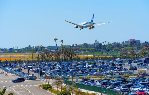 Close-up view of the tightly packed LAX Parking lots with an airplane flying above.