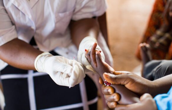 A nurse administers a malaria test to a young child at a health care centre in Guinea. Credit: Jake Lyell.