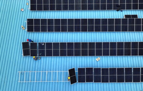 Workers install solar photovoltaic panels on the roof of a factory in Haian, Jiangsu province on 11 April 2024.