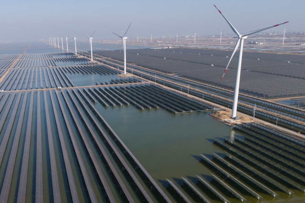 Wind turbines dot the coast line along a giant solar farm near Weifang in eastern China's Shandong province on 22 March 2024.