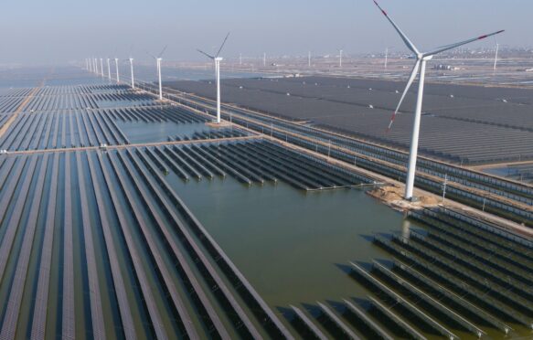 Wind turbines dot the coast line along a giant solar farm near Weifang in eastern China's Shandong province on 22 March 2024.