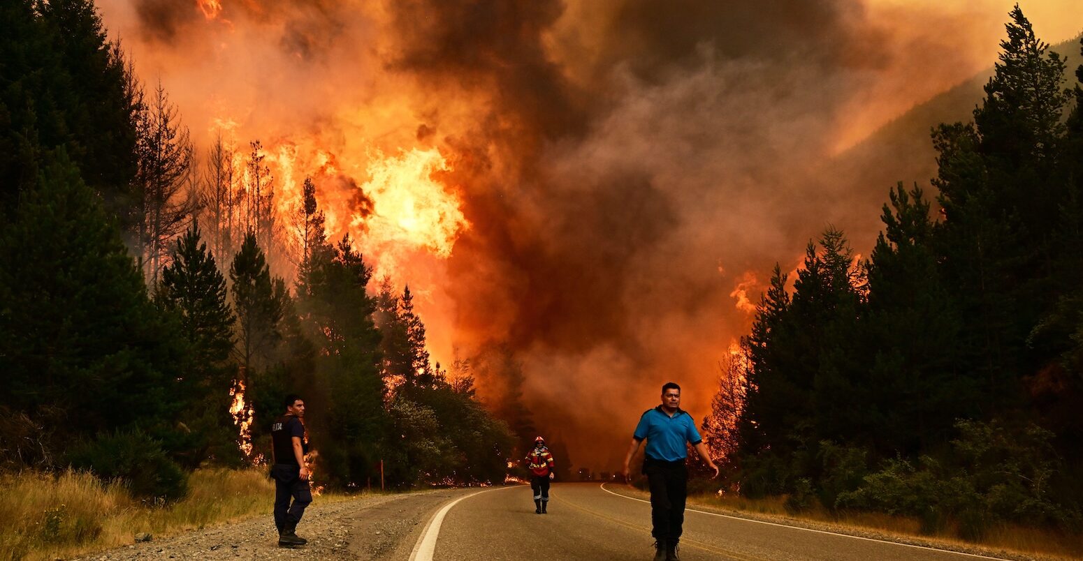 People walking on a road as a wildfire blazes behind them in Argentina, January 2026. Credit: Associated Press / Alamy Stock Photo.