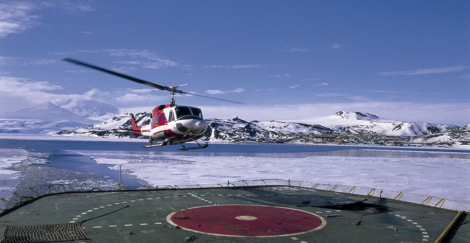 Helicopter landing on icebreaker deck near US scientific research base on Ross Island, Antarctica. Image ID: A1E4K4