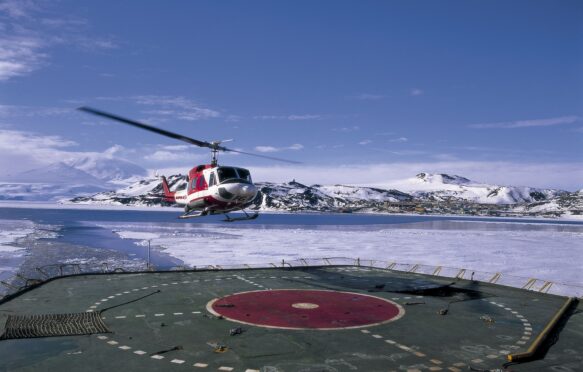 Helicopter landing on icebreaker deck near US scientific research base on Ross Island, Antarctica. Image ID: A1E4K4