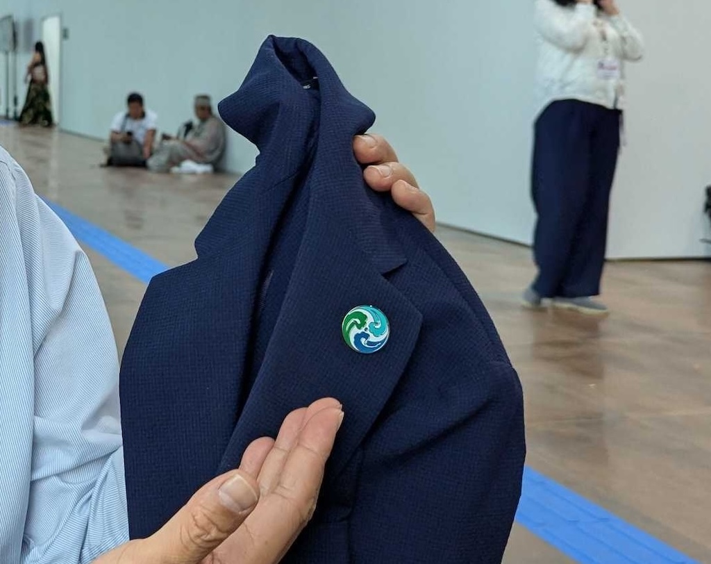 IPE director Ma Jun showing a pin based on his organisation’s logo. Photo credit: Carbon Brief