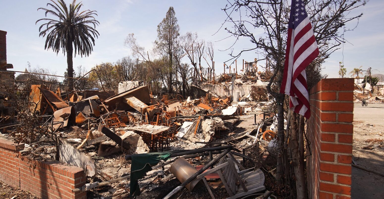 A flag of the United States is seen in front of a burnt house during the Palisades wildfire in January 2025.