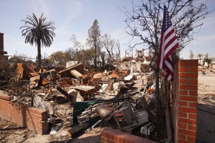 A flag of the United States is seen in front of a burnt house during the Palisades wildfire in January 2025.