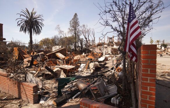 A flag of the United States is seen in front of a burnt house during the Palisades wildfire in January 2025.
