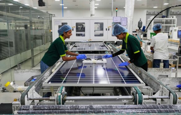 Workers put switches and connectors on solar panels at a factory in Jaipur, India.