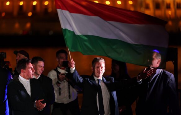 Peter Magyar, leader of Hungary's Tisza Party, waves the Hungarian national flag at an election victory rally.