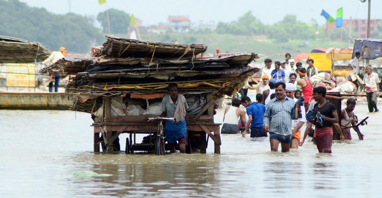 People moving their belongings after a flooding incident in the River Ganga area.