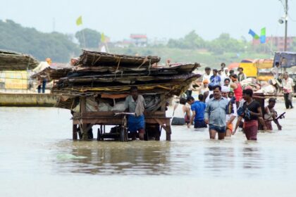 People moving their belongings after a flooding incident in the River Ganga area.