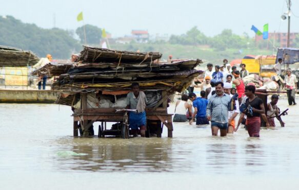 People moving their belongings after a flooding incident in the River Ganga area.