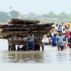 People moving their belongings after a flooding incident in the River Ganga area.