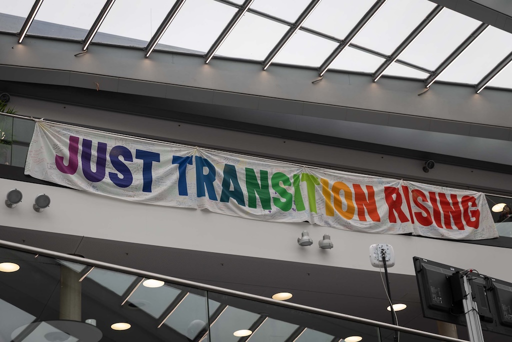 As the second week of the June Climate Meetings kicks off, members of civil society drop a banner in the main foyer, reminding delegates of the need for a just transition.