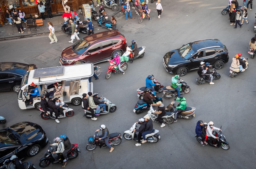 An electric sightseeing bus, motorcycles and cars in central Hanoi, Vietnam.